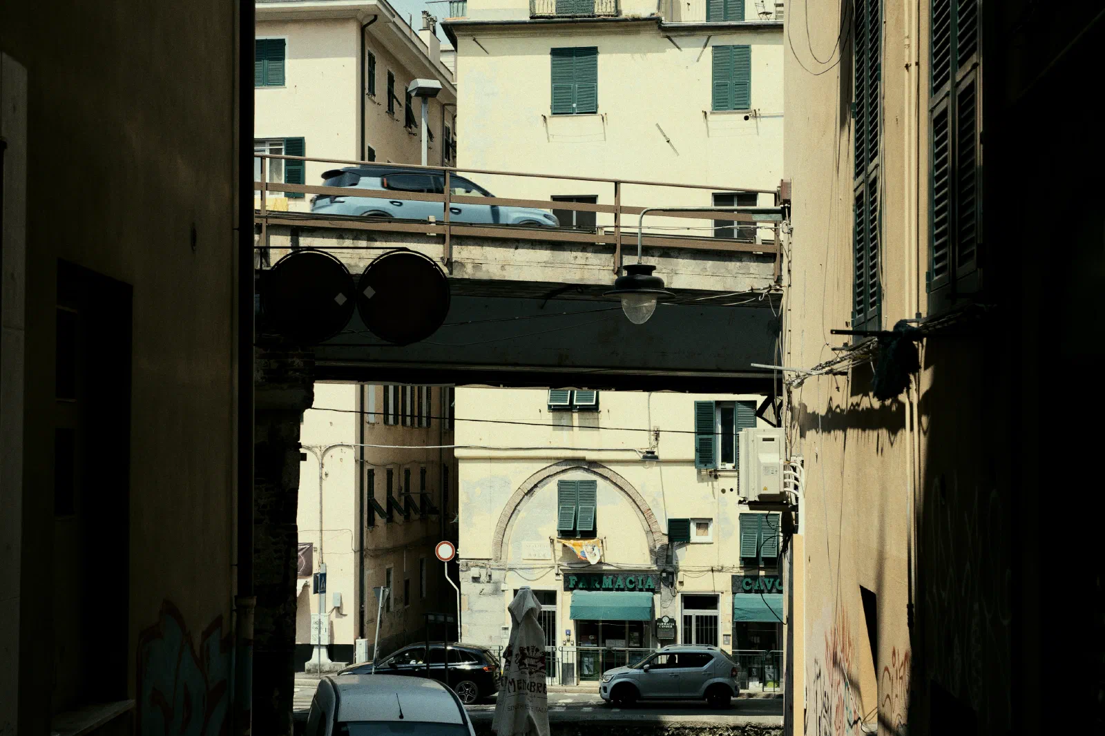 a raised highway cutting through a Genovese neighborhood, a card drives on it